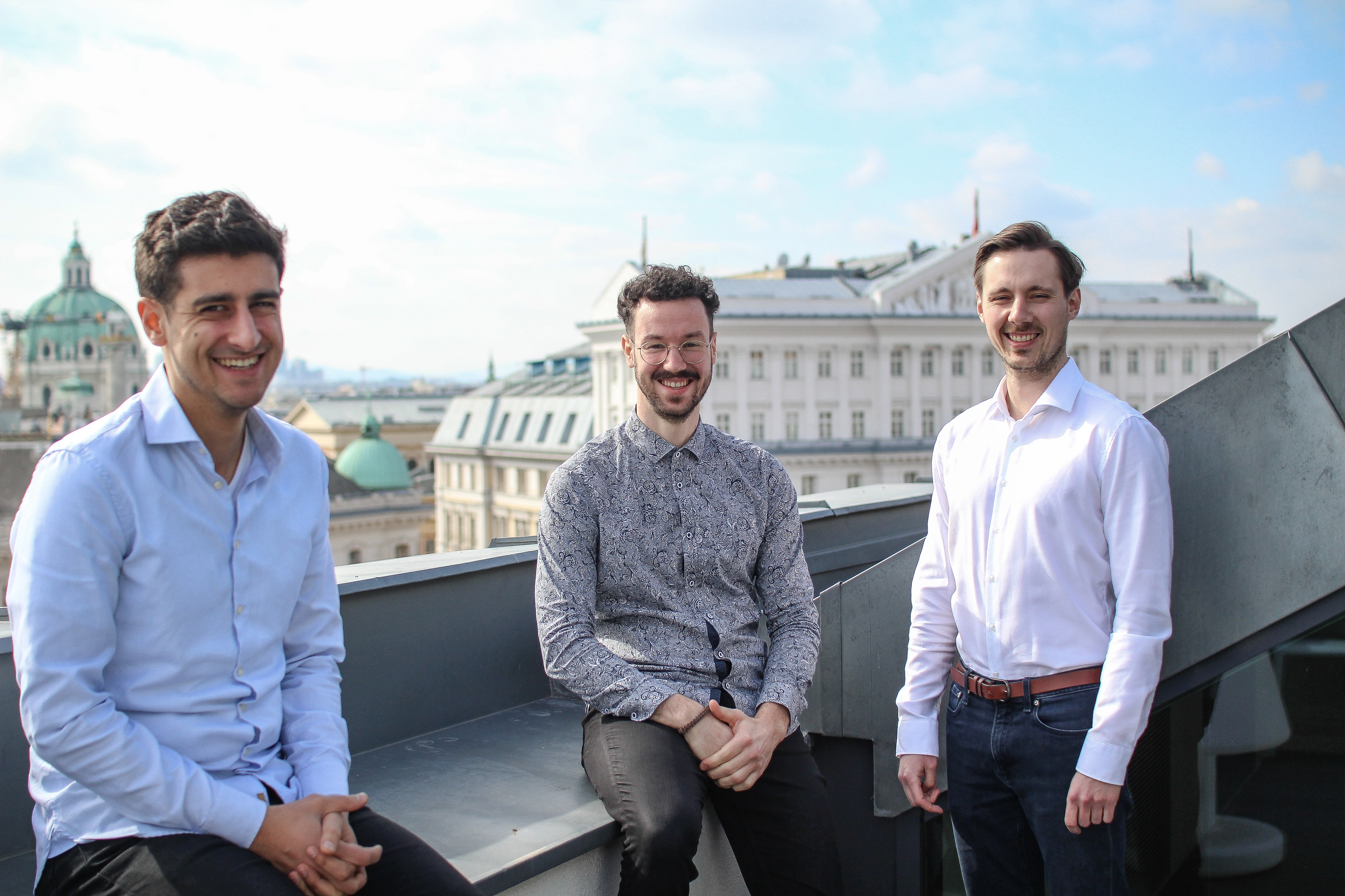 Three of the male founders are standing on a rooftop and smiling at the camera.